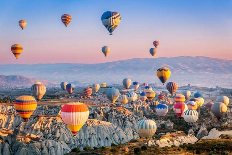 Khinh khí cầu bay lên phía trên thung lũng đá Cappadocia lúc bình minh