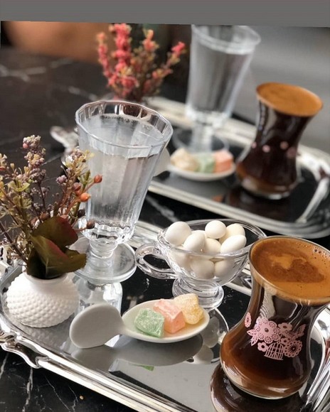 Ly raki màu trắng đục bên cạnh ly nước lọc và đĩa phô mai trắng