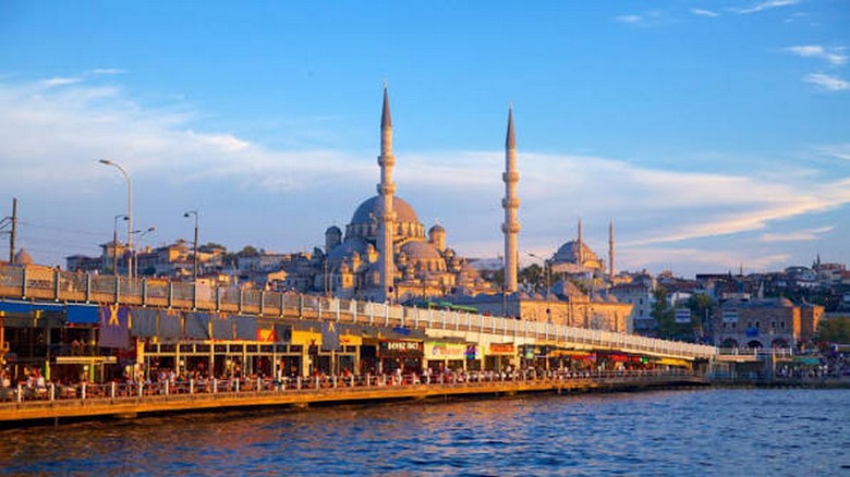 Thuyền du lịch di chuyển trên eo biển Bosphorus với cầu nối hai châu lục phía sau